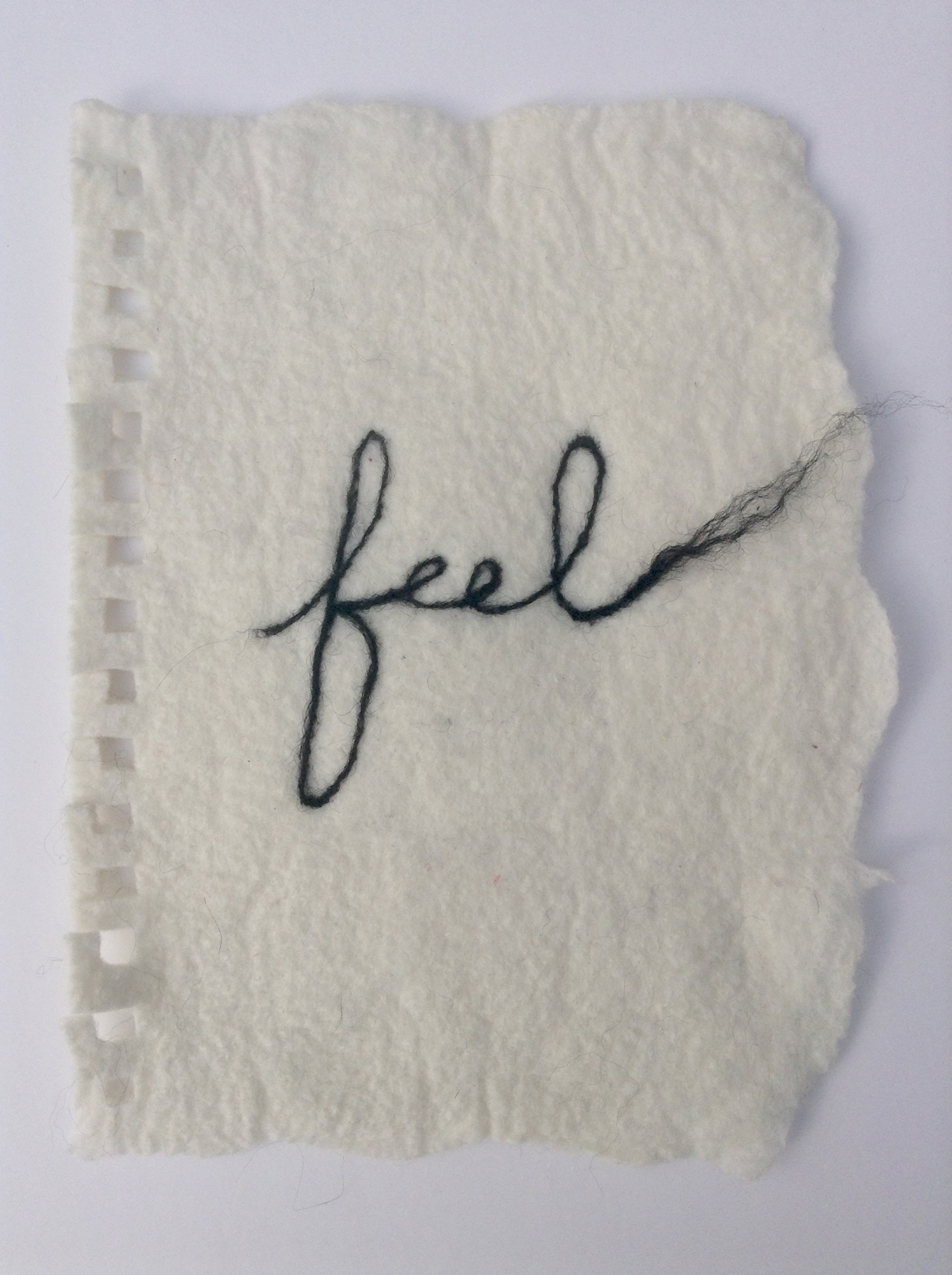 The word Feel is felted on a white wet felted sheet that mimics a torn piece of paper.